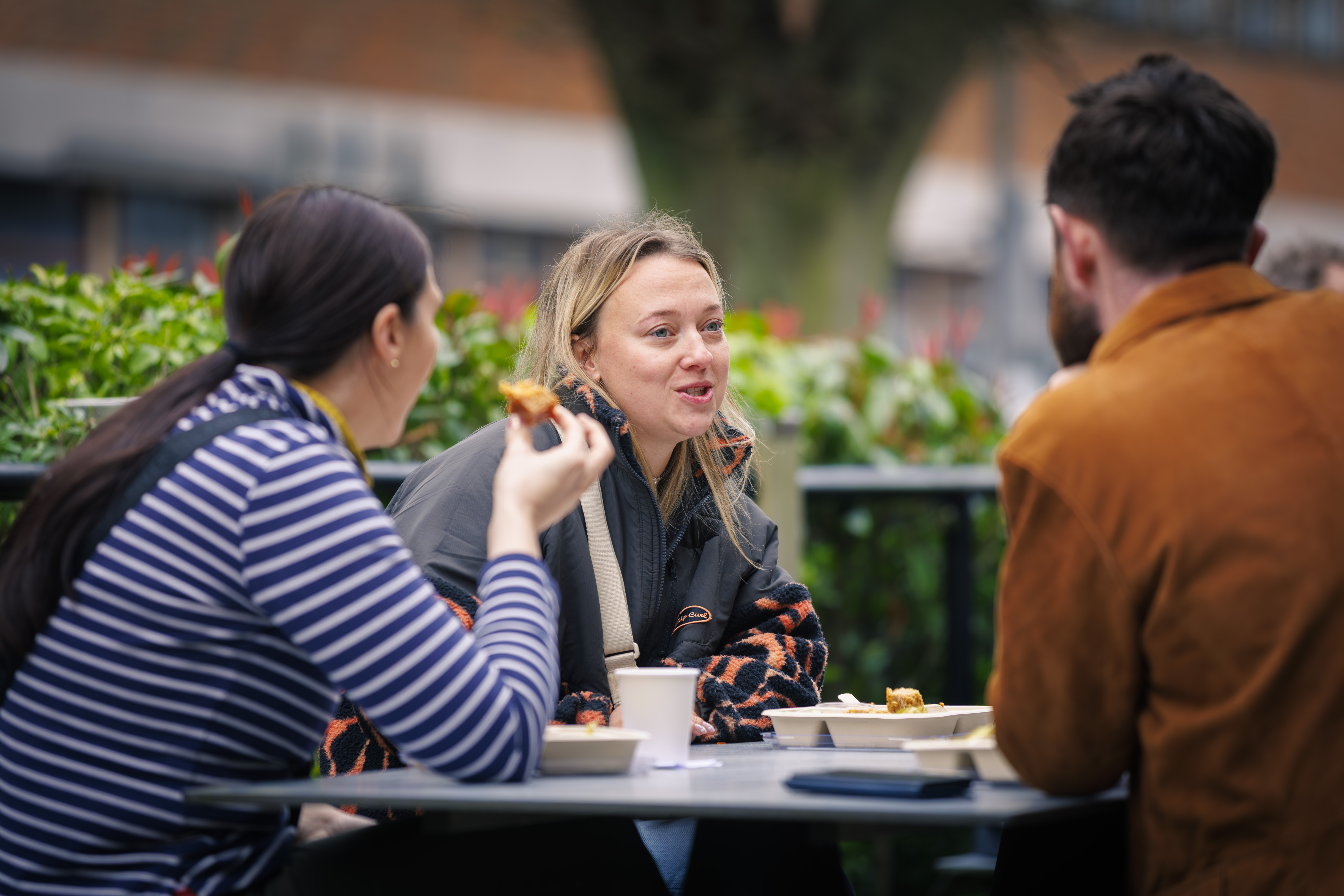 People sit eating outside Canham Turner surrounded by green hedges