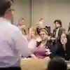 A group of conference attendees listen to a speaker