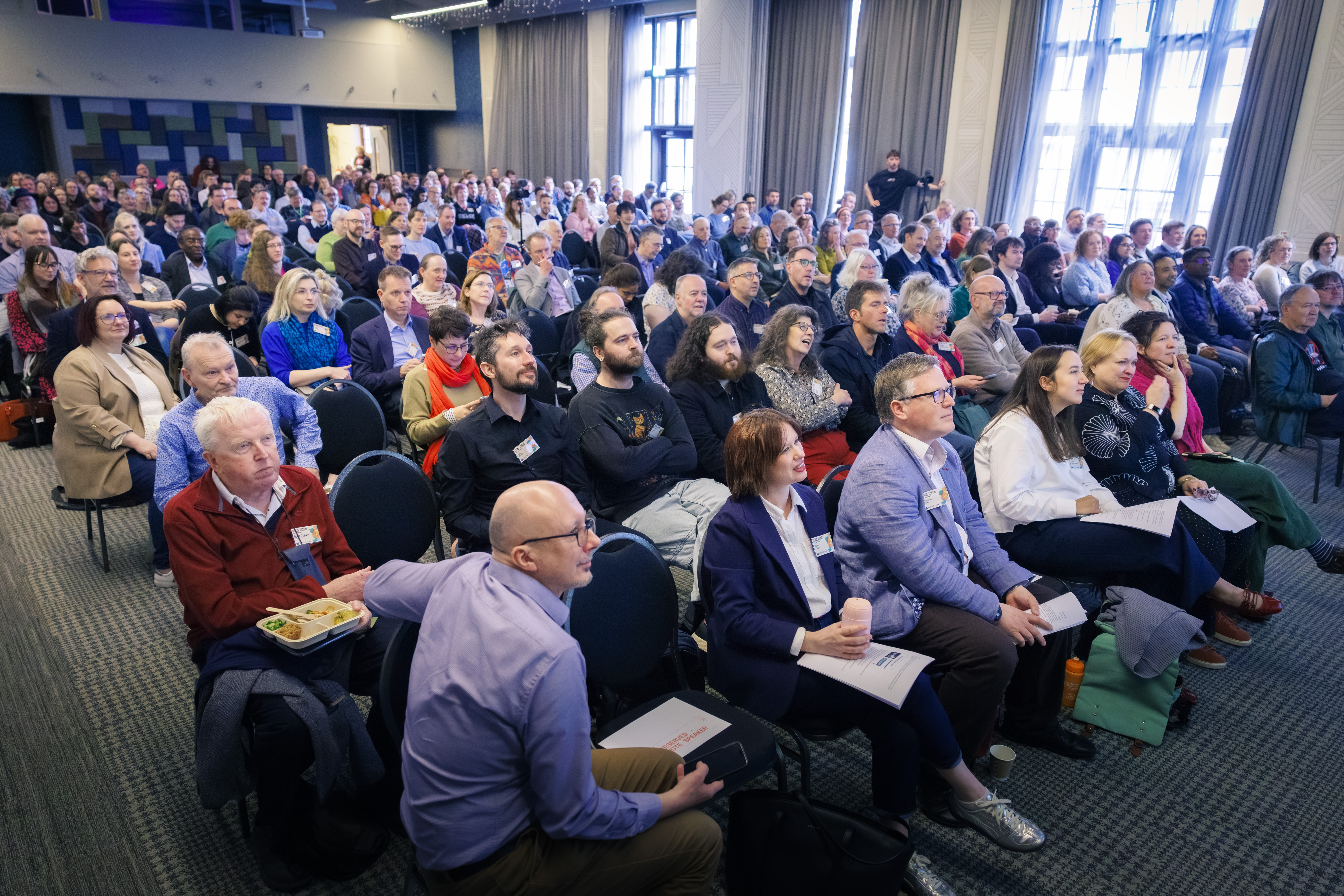 A large crowd of attendees sitting in rows at a conference