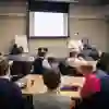 Groups of people sit around tables in a conference break out session
