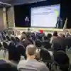 A handful of people watch a presentation in a large conference room that's partitioned in half