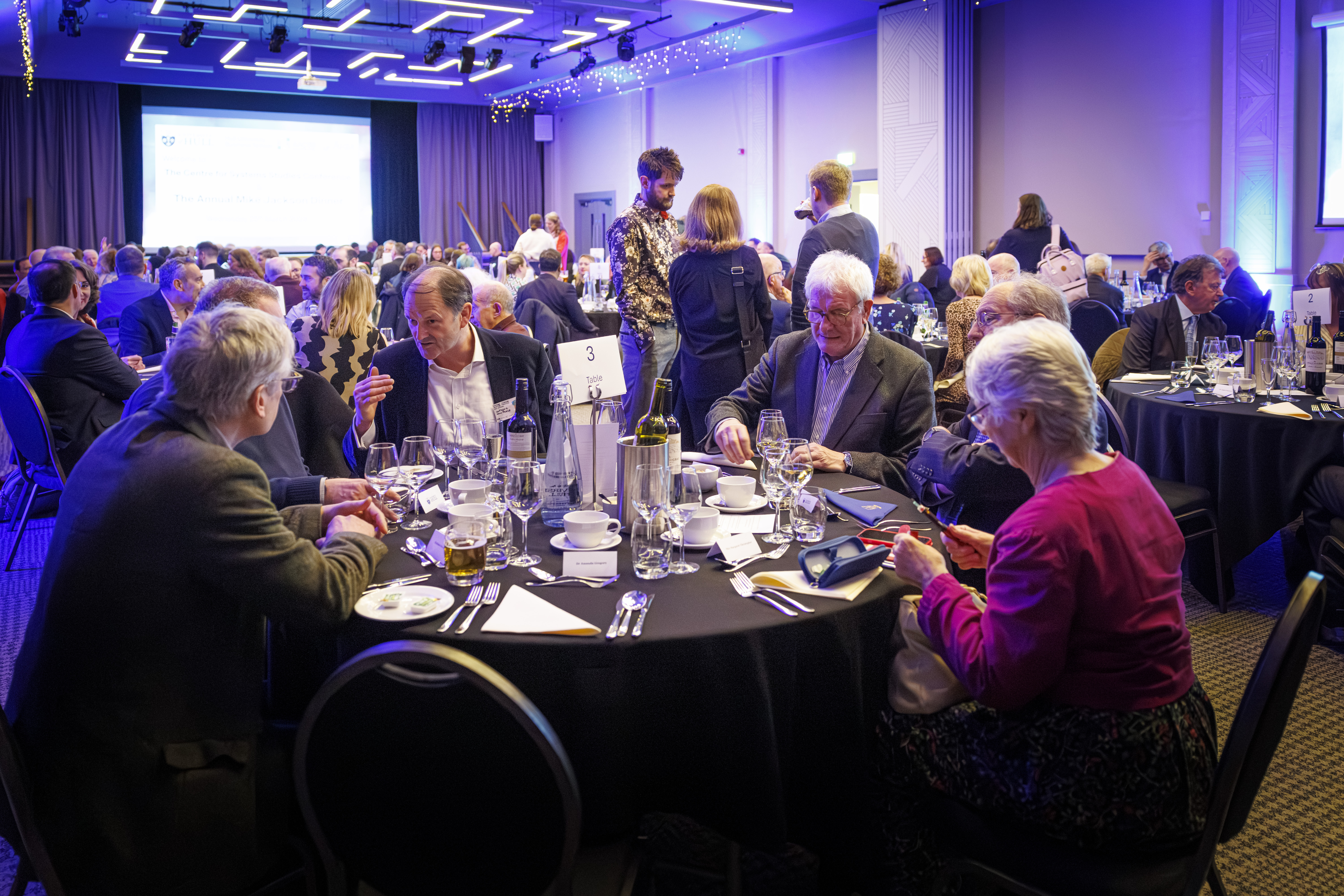 A group of delegates talk animatedly at a round table at a conference function