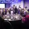 A group of delegates talk animatedly at a round table at a conference function