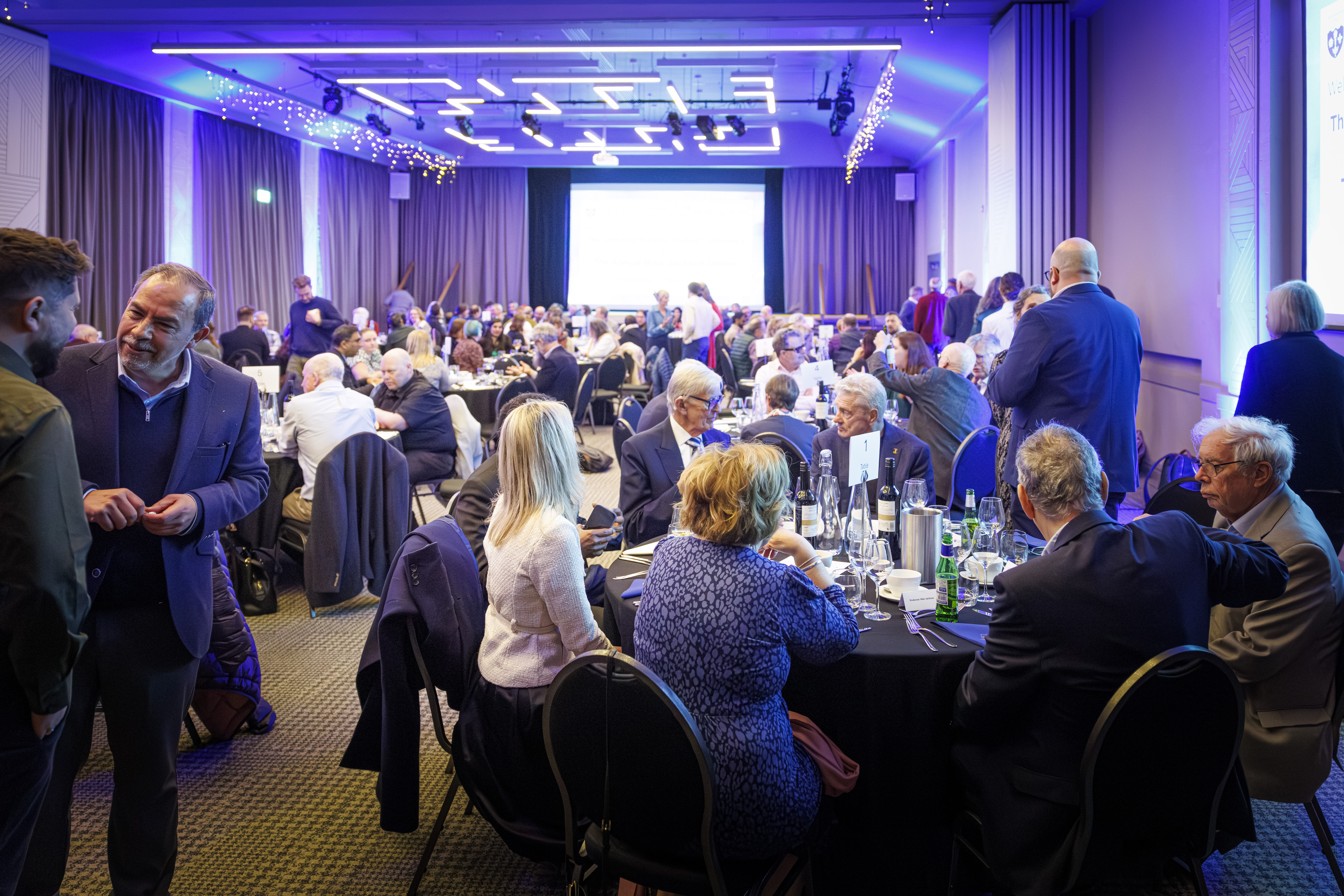 People sit around tables at a formal dining event