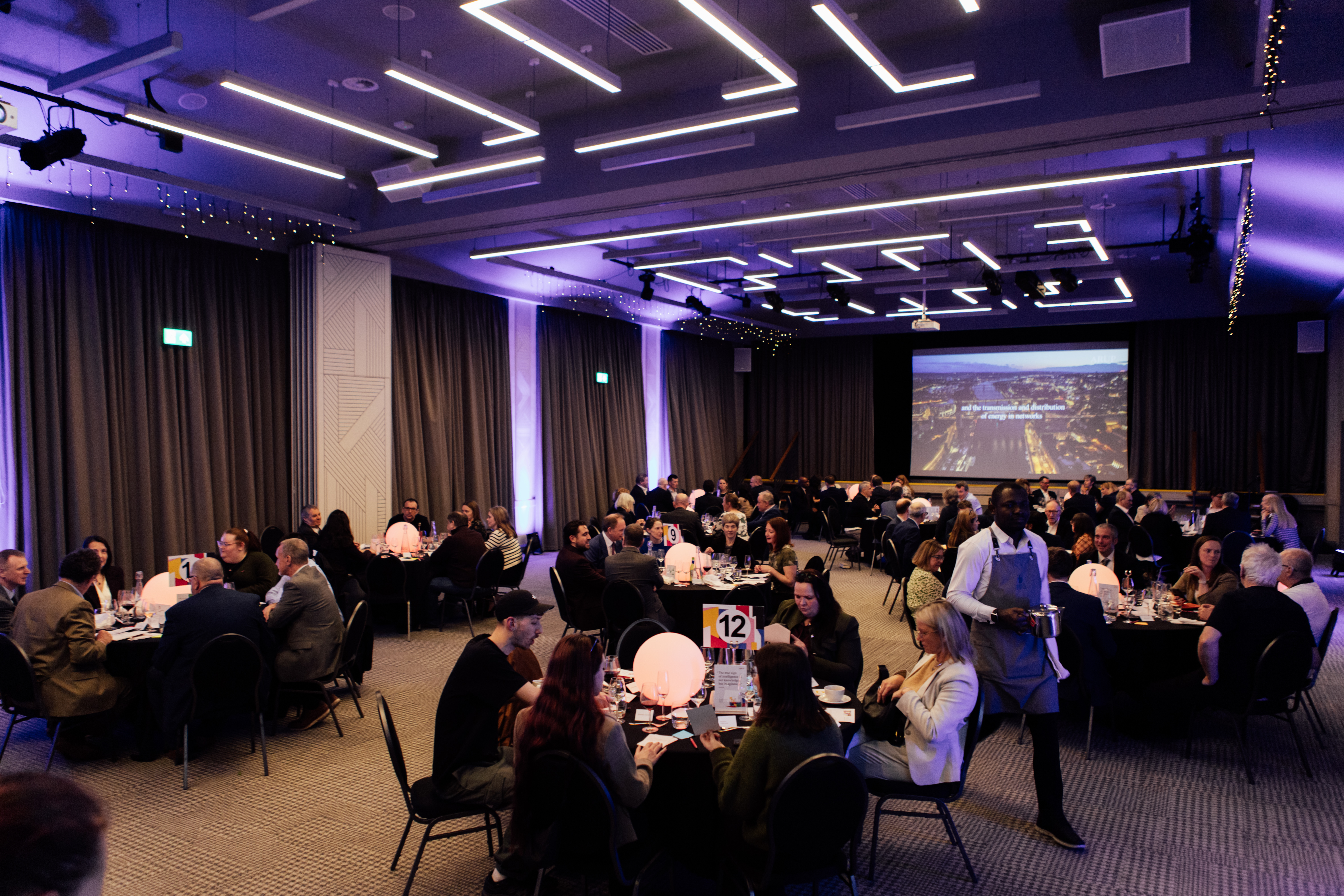 Business representatives sit at round tables for a meal as part of a conference function