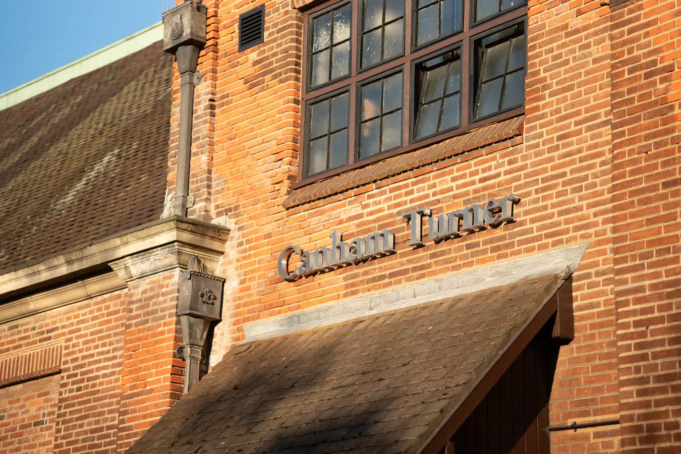 A close up on the metal Canham Turner sign on the side of the red-brick conference building