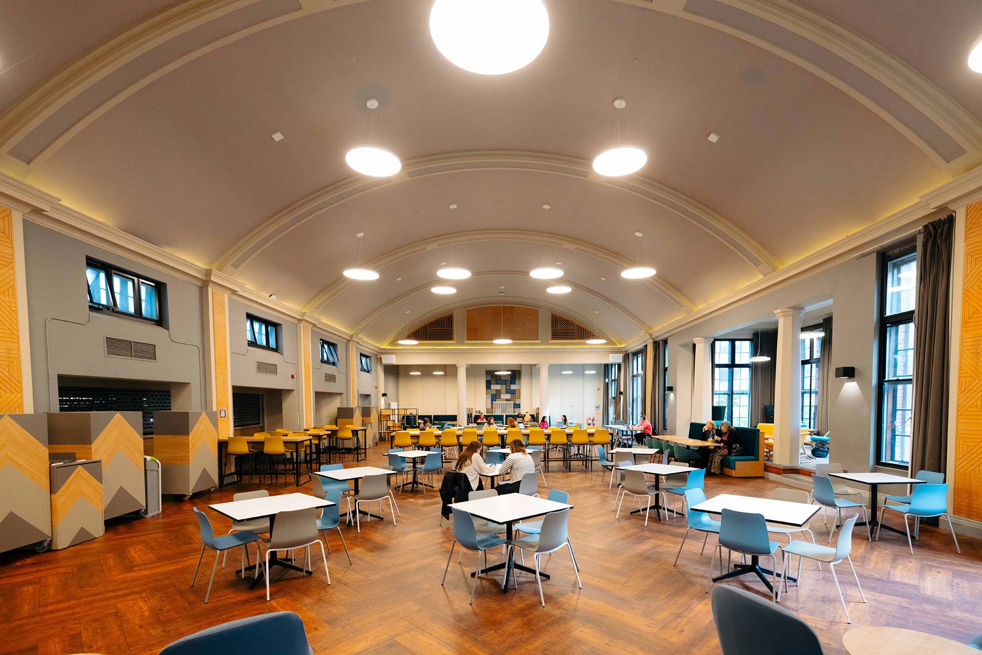 A handful of people sit in a large dining room 