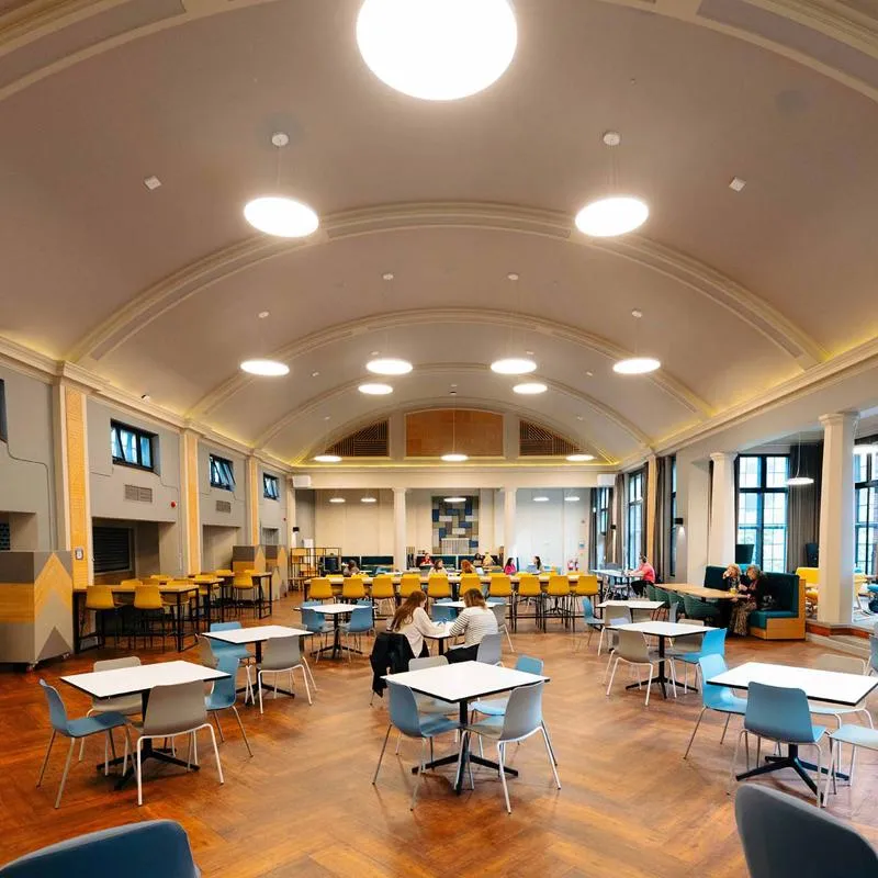 A handful of people sit in a large dining room