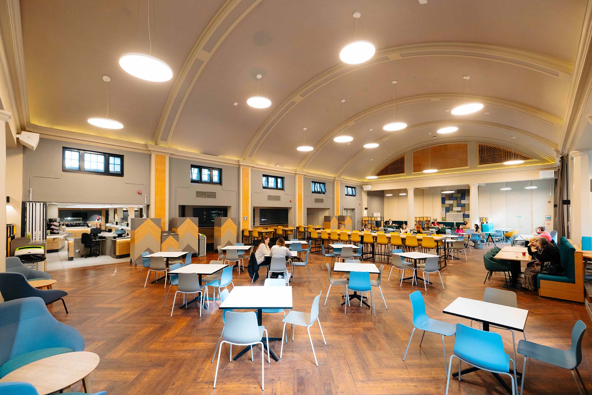 A handful of people sit in a large dining room 