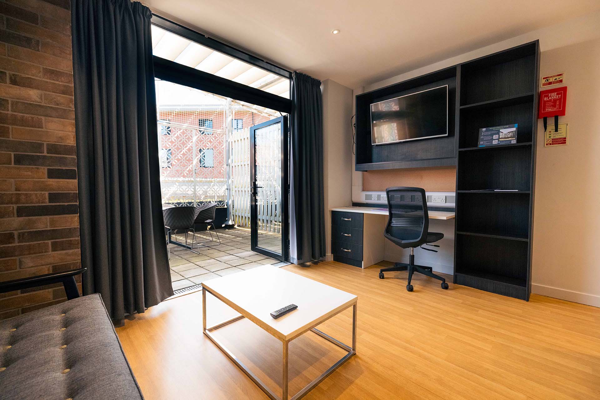 Spacious desk area in a rooftop flat at The Courtyard with balcony doors open to an outdoor patio space.
