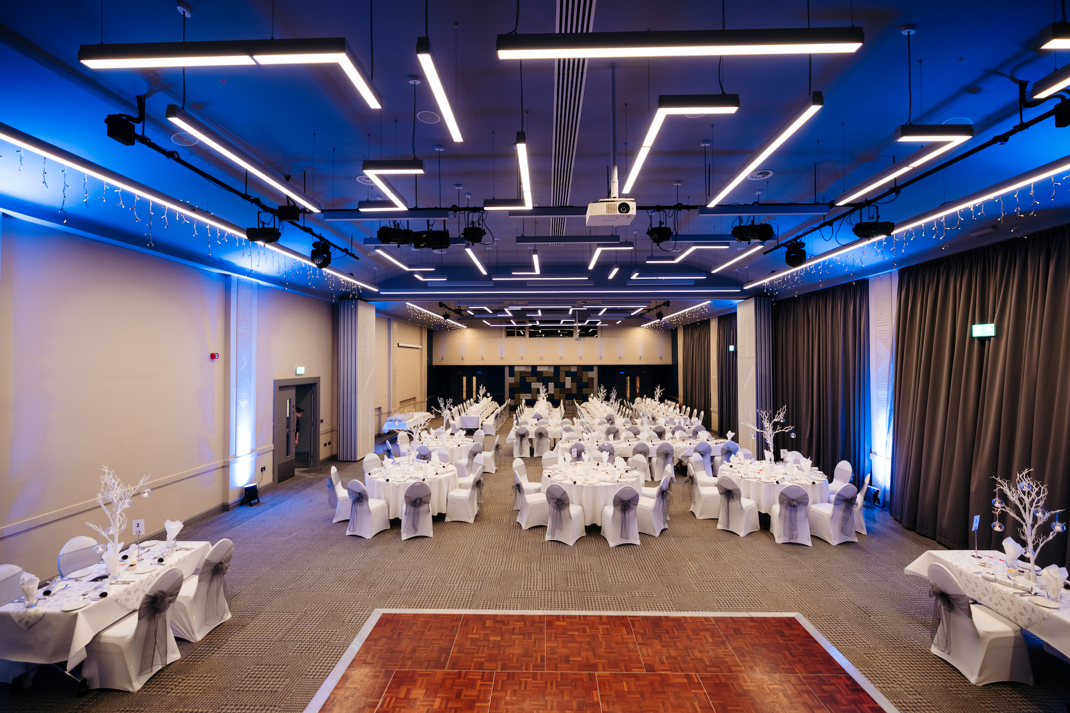 A wide view of many tables set up for dinner in the Kingsley Suite
