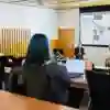 A man gives a presentation in a small wood panelled lecture room
