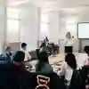 A woman gives a presentation to a small group of students in an executive boardroom